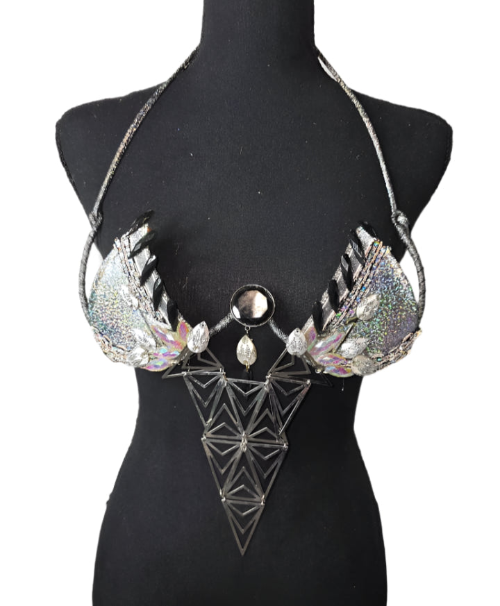 Silver Prism Decorated Wire Bra featuring a sparkling silver base, holographic gems, reflective accents, and a dramatic geometric centerpiece, displayed on a black mannequin—perfect for carnivals, samba dancers, and festival performances. #CarnivalMW #CarnivalReady #FestivalFashion #WireBra #SilverPrism #ShowgirlStyle #CustomCostumes #carnivalfeathers #carnivalcostume #carnivalbackpack #festival #festivalwear #festivallooks #carnival #mondaywear
Silver Prism Decorated Wire Bra with a front view showcasing t