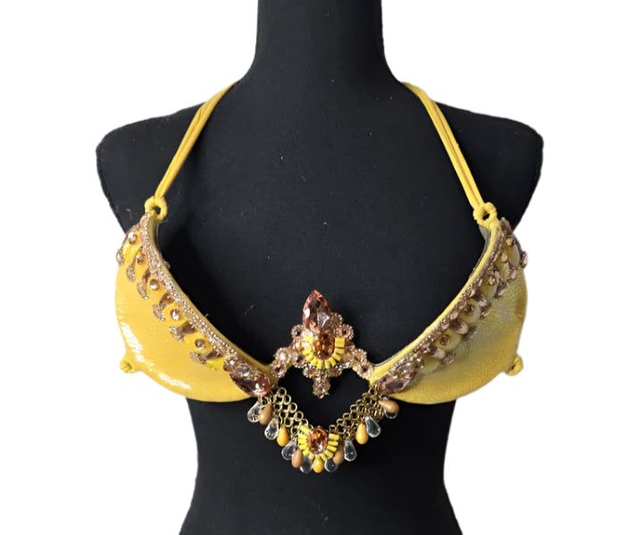 Sun Goddess Decorated Wire Bra featuring a vibrant yellow wire base, radiant gold and amber gem embellishments, and intricate chain accents, displayed on a black mannequin—perfect for carnivals, samba dancers, and festival performances. #CarnivalMW #CarnivalReady #FestivalFashion #WireBra #SunGoddess #ShowgirlStyle #CustomCostumes #carnivalfeathers #carnivalcostume #carnivalbackpack #festival #festivalwear #festivallooks #carnival #mondaywear