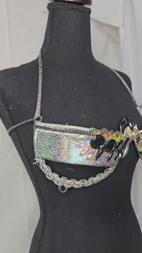 Cosmic Starlight Decorated Wire Bra featuring holographic silver fabric, iridescent crystal gems, and black gemstone accents, displayed on a black mannequin—perfect for carnivals, festivals, and sparkling performances. #CarnivalMW #FestivalFashion #CarnivalReady #WireBra