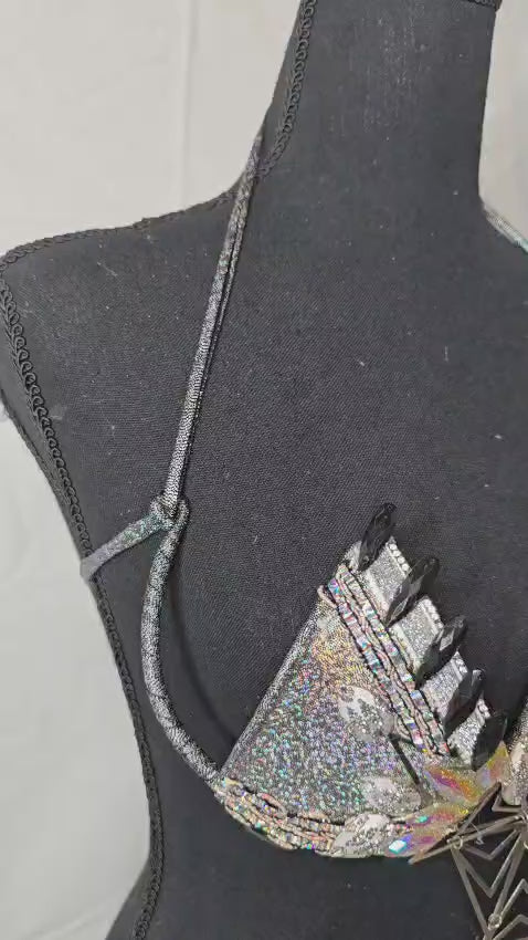 Silver Prism Decorated Wire Bra featuring a sparkling silver base, holographic gems, reflective accents, and a dramatic geometric centerpiece, displayed on a black mannequin—perfect for carnivals, samba dancers, and festival performances. #CarnivalMW #CarnivalReady #FestivalFashion #WireBra #SilverPrism #ShowgirlStyle #CustomCostumes #carnivalfeathers #carnivalcostume #carnivalbackpack #festival #festivalwear #festivallooks #carnival #mondaywear
Silver Prism Decorated Wire Bra with a front view showcasing t